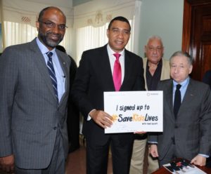 Andrew Holness (center), Prime Minister of Jamaica, displays his signed pledge to save kids lives as part of the UN Decade of action for Road Safety following a courtesy call made on his office on Tuesday, August 9, by Jean Todt (second right), the United Nations Special Envoy for Road Safety and President of the President of the Fédération Internationale de l'Automobile (FIA) and Earl Jarrett (left), President of the Jamaica Automobile Association (JAA) as Michael Henry, Minister of Transport and Mining, looks on.